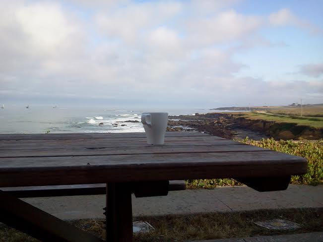 Mesa con taza de café con el mar de fondo